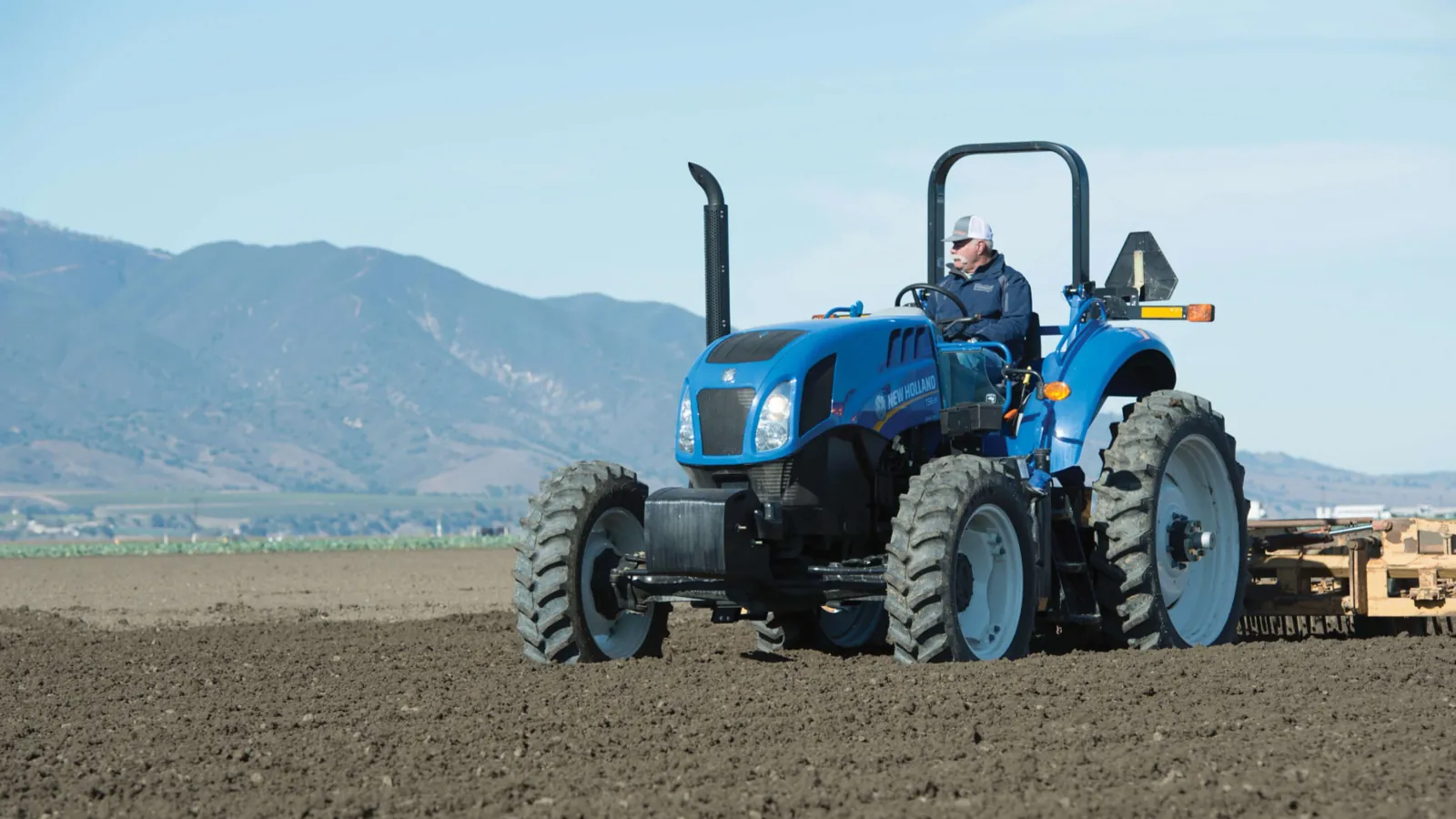 Representative New Holland TS6 Series II tractor working a cultivated field