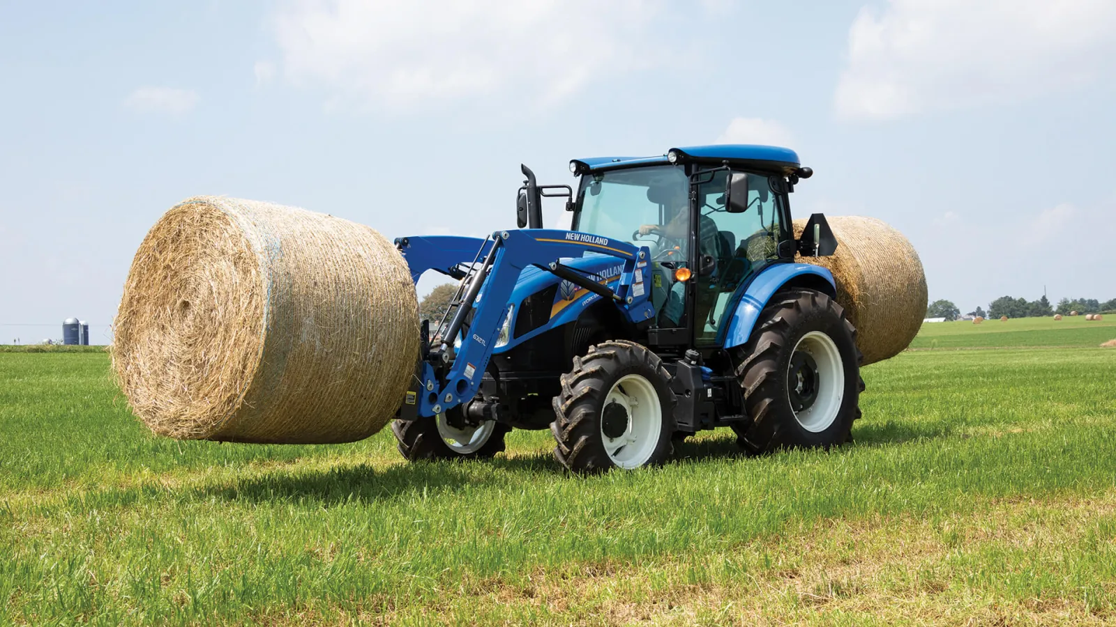 Representative New Holland WORKMASTER PLUS tractor carrying round hay bales