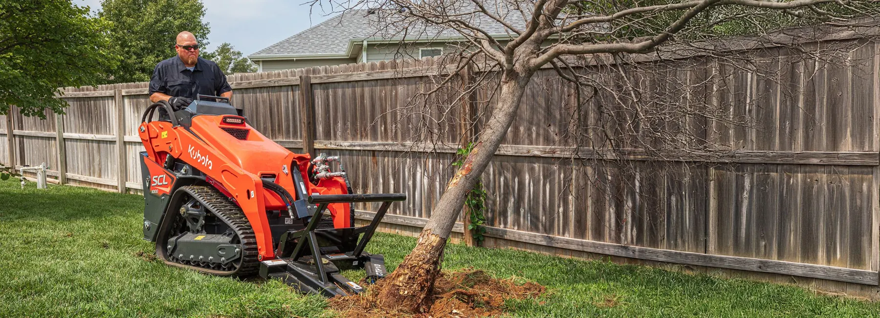 Kubota compact track loader removing a tree on a residential jobsite